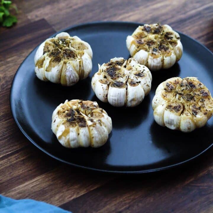 Roasted Garlic served in a black plate.
