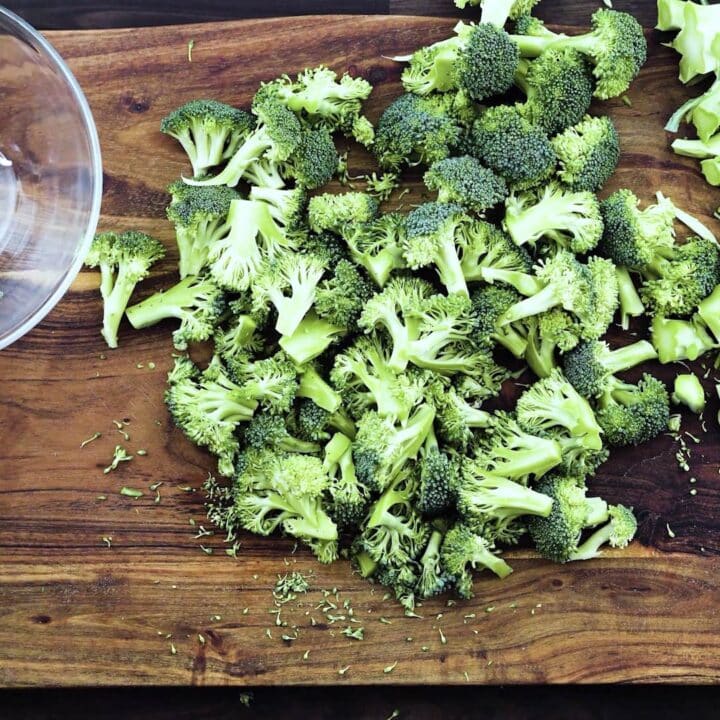 Separated Broccoli florets on a cutting board.