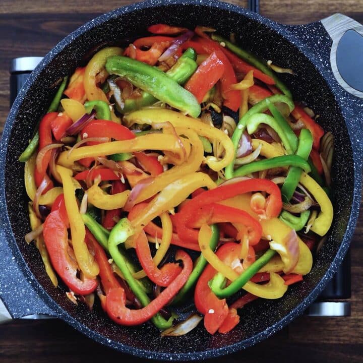 A pan with sauteed bell peppers and onions.