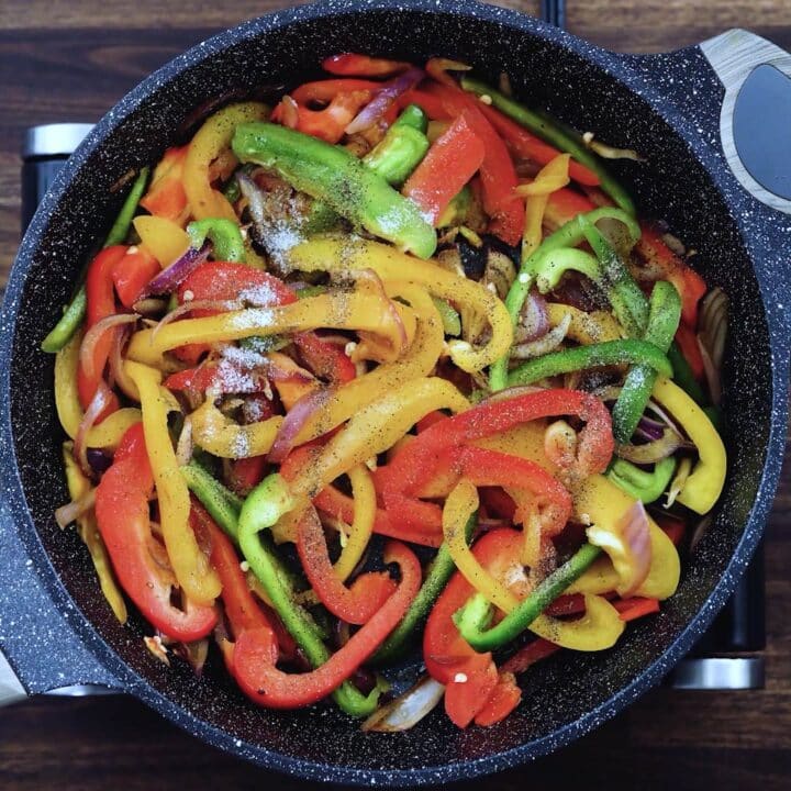 A pan with bell peppers and onions seasoned with pepper and salt.