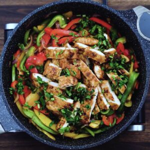 A pan with chicken fajita garnished with cilantro leaves.