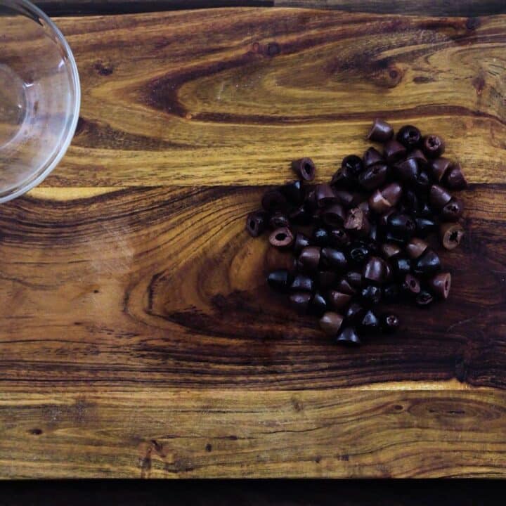 Sliced Kalamata olives on a cutting board.