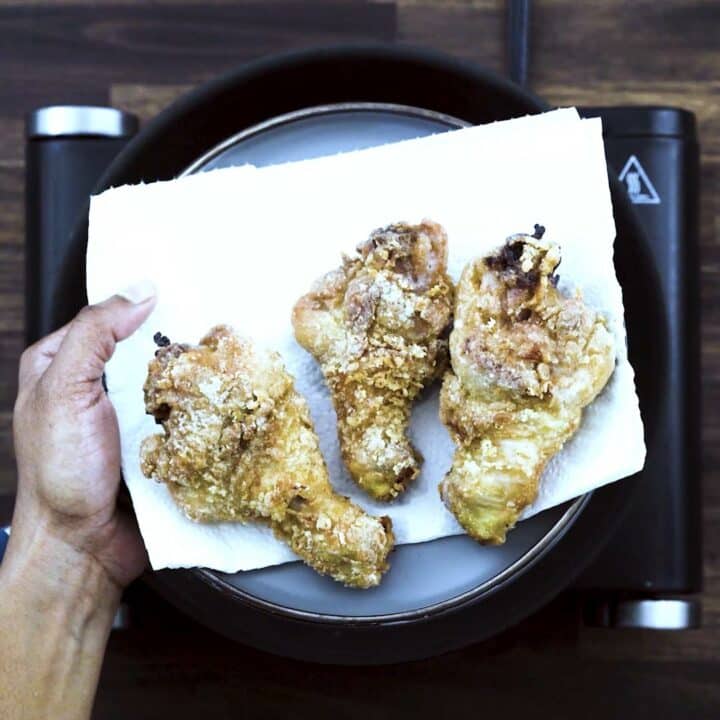 Fried Chicken Drumsticks on a black plate lined with tissue paper.