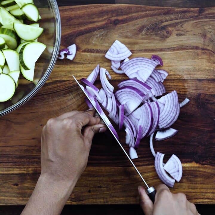 Slicing the red onion using a knife.