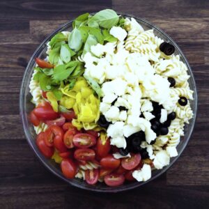 A bowl with pasta, veggies and savory toppings.