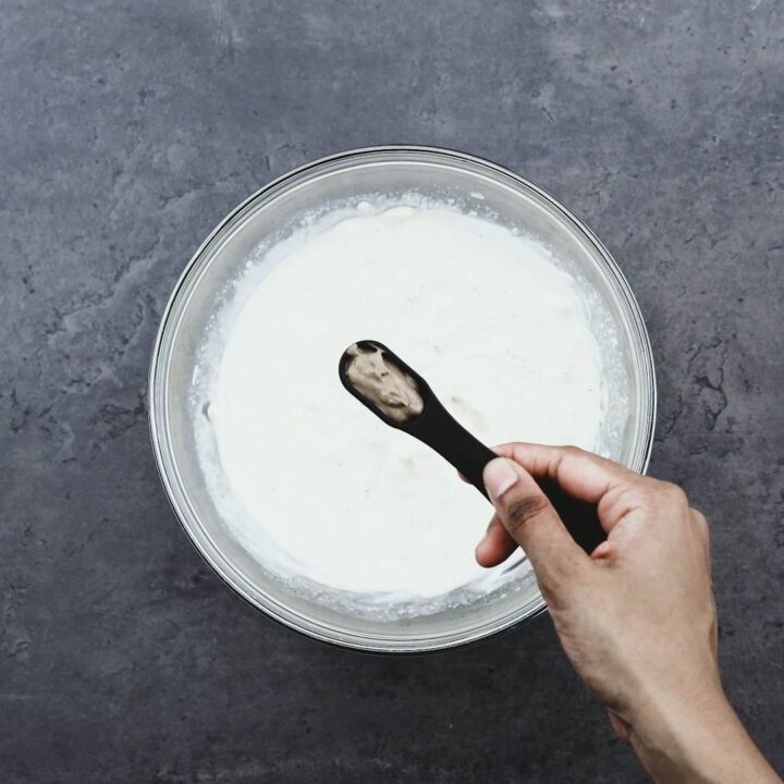 Adding anchovy paste to the bowl of creamy mayo.