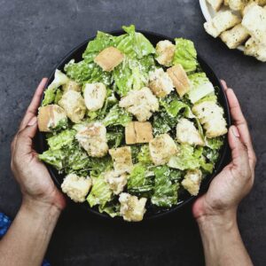 Serving the Caesar Salad in a black bowl.