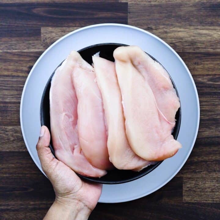 Thinly sliced chicken breast on a black plate.