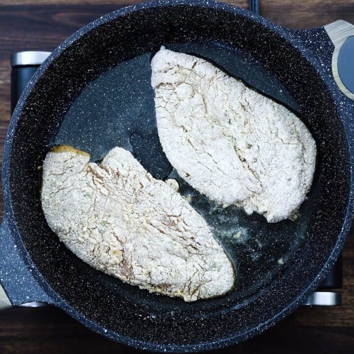 Breaded chicken breast frying in a pan.