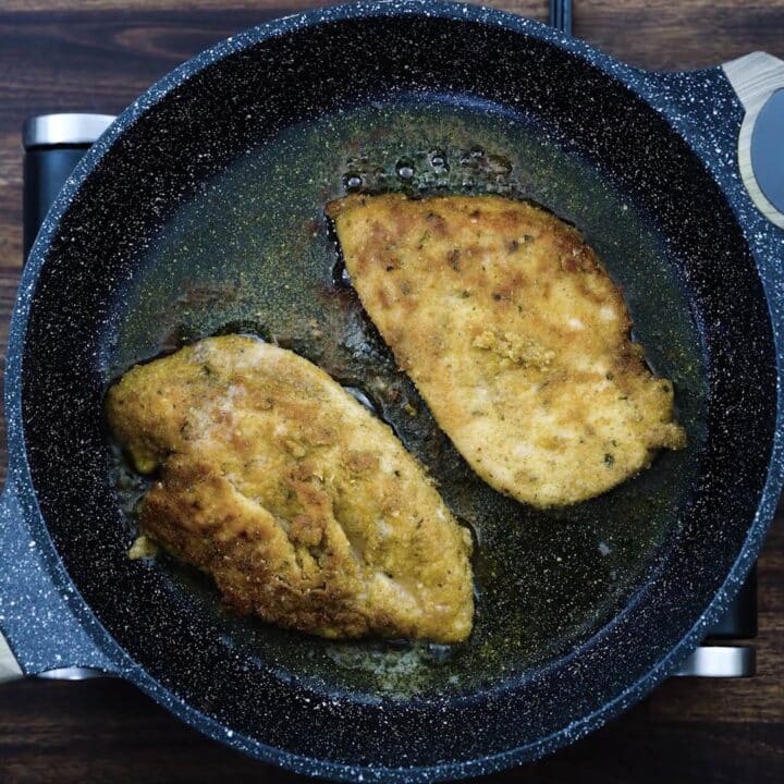 Golden brown chicken breast in a frying pan.