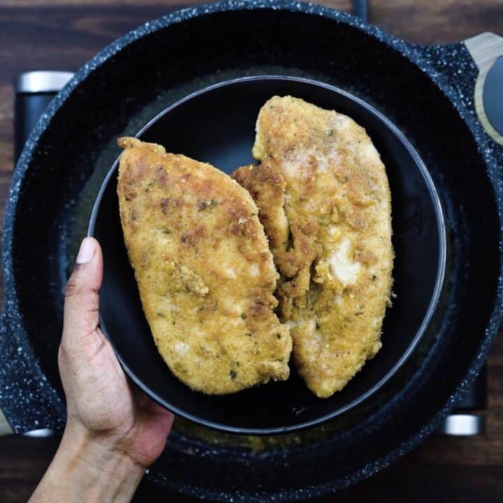 A black plate with fried chicken cutlets.