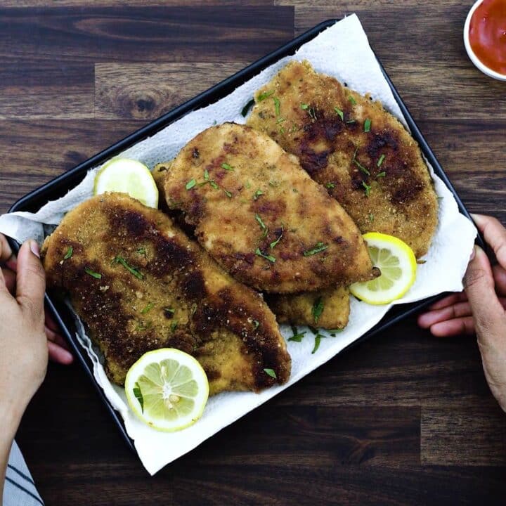 Serving Chicken Cutlets in a tray with lemon slices.