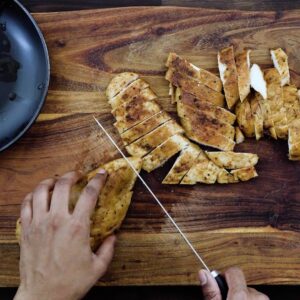 Slicing the baked chicken breast using a knife.