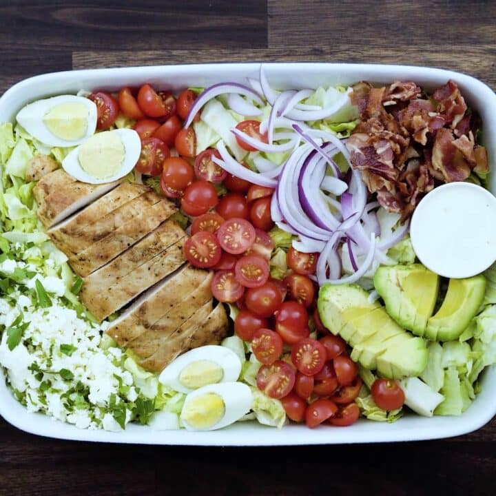A tray with cobb salad and ranch dressing.