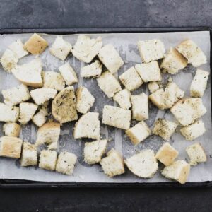 Seasoned bread cubes in a baking tray.