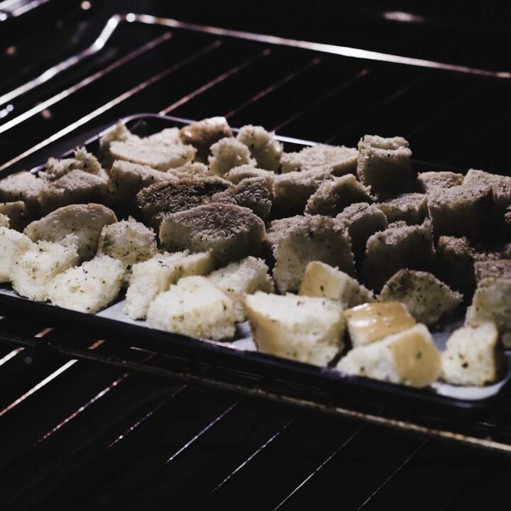 A tray with bread cubes inside the oven.