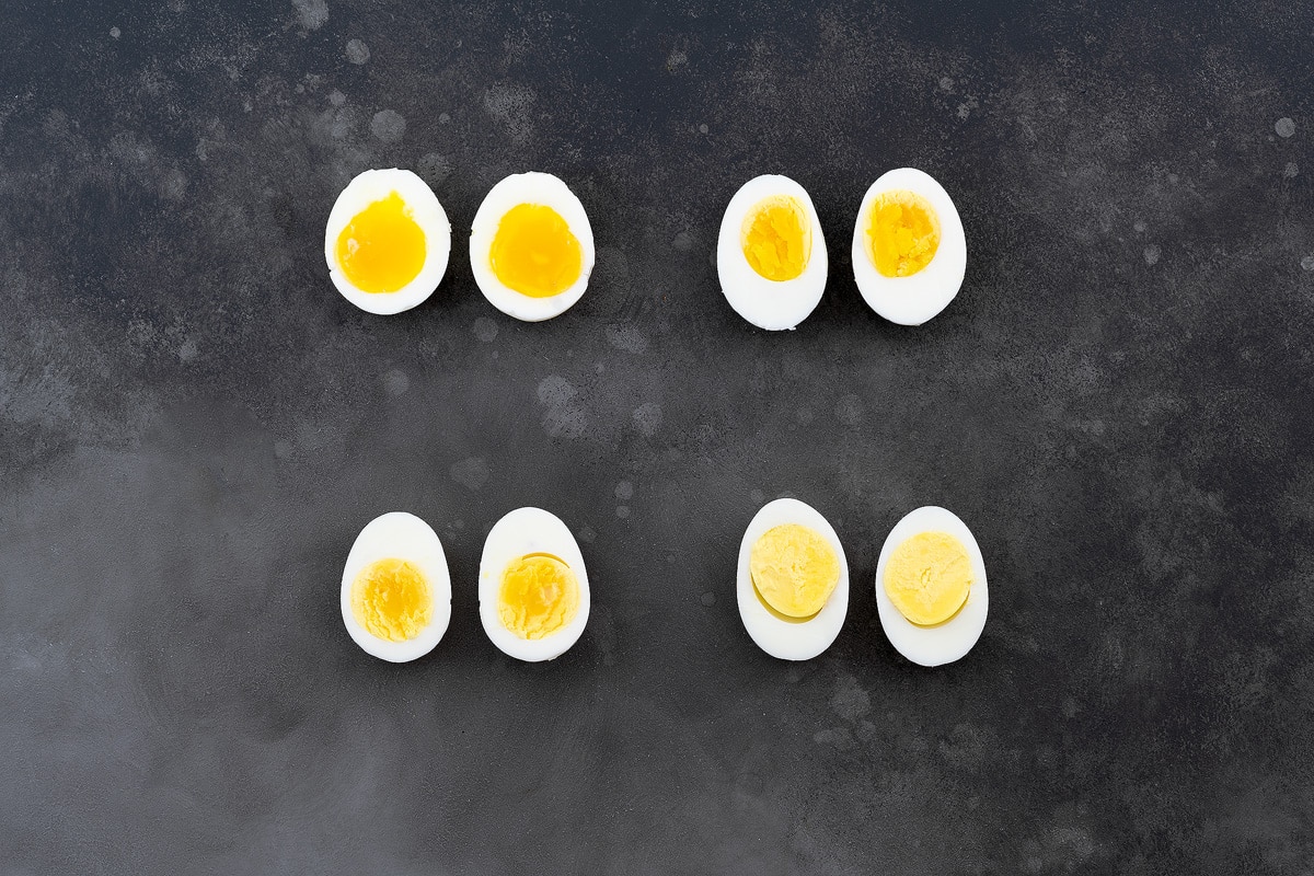Runny to Creamy Perfectly Soft and Hard Boiled Eggs, halved and arranged on a gray table.