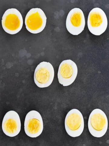 Runny to Creamy Perfectly Soft and Hard Boiled Eggs, halved and arranged on a gray table.