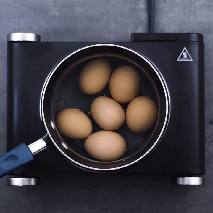 A sauce pan with eggs in water.
