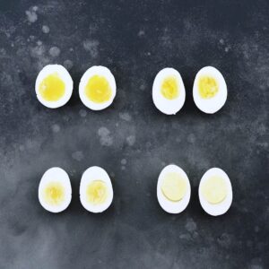 Soft and hard boiled eggs on a grey board.