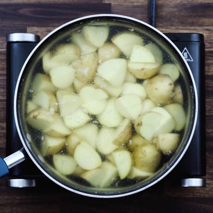 A wide pan with cubed potatoes in water.