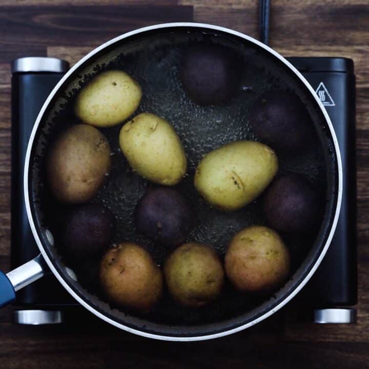 A pot with whole potatoes in a water.