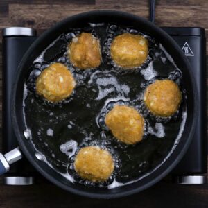 Golden Hush Puppies frying in oil.