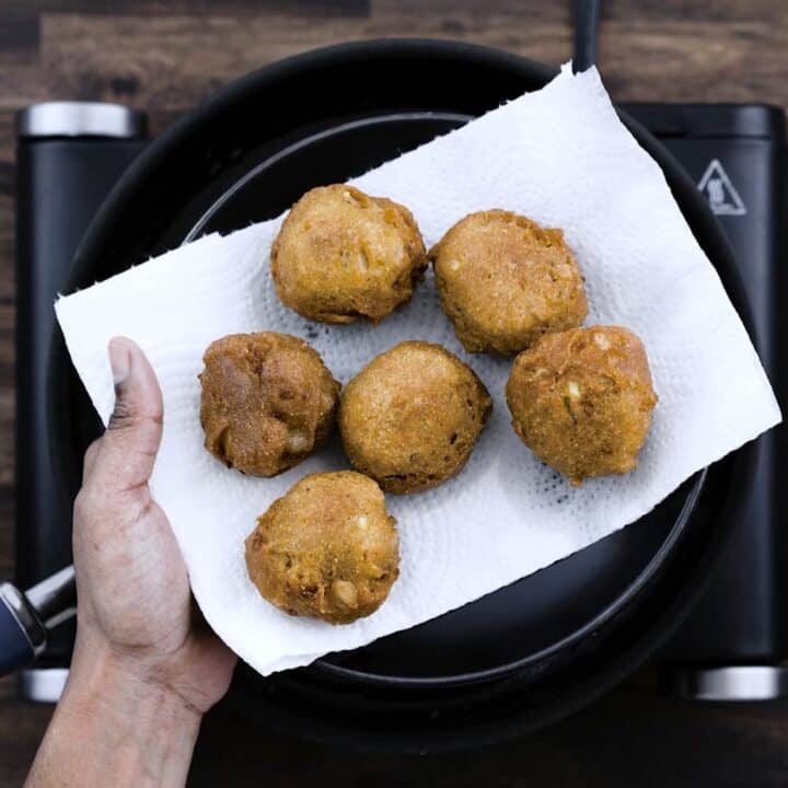 Golden brown Hush Puppies on a black plate.