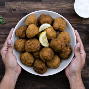 Serving Hush Puppies with lemon slices in a serving bowl.