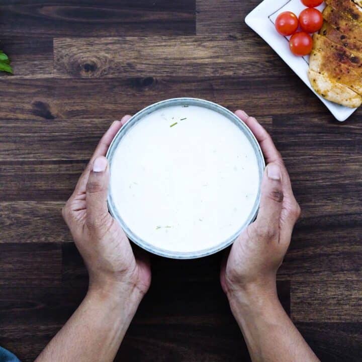 Serving Ranch Dressing in a bowl alongside baked chicken breast and cherry tomatoes.
