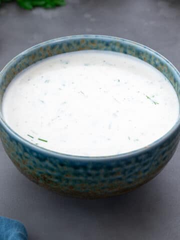 Close-up of ranch dressing in a green and blue patterned bowl.