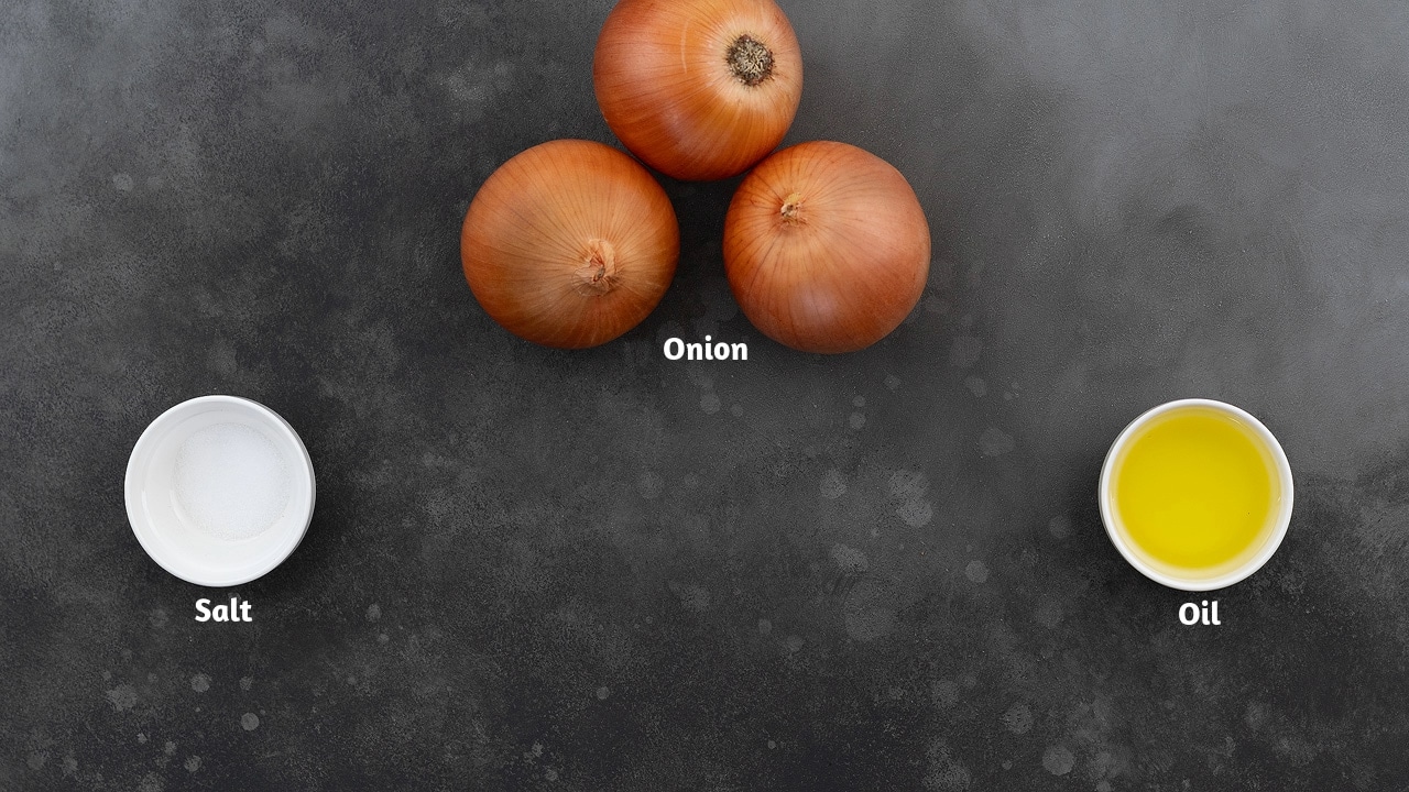 A gray table with ingredients for caramelized onions: onions, salt, and oil.