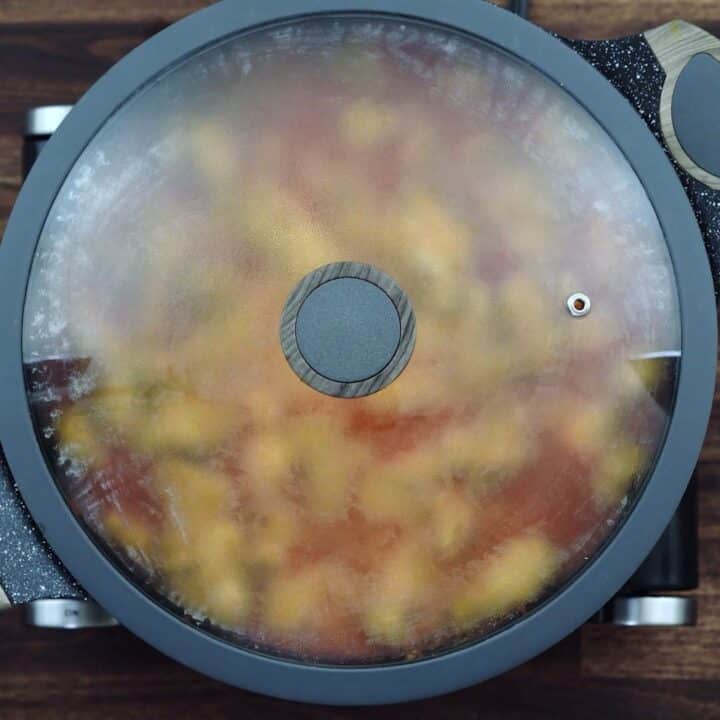 Chicken mixture cooking in a pan with its lid closed.