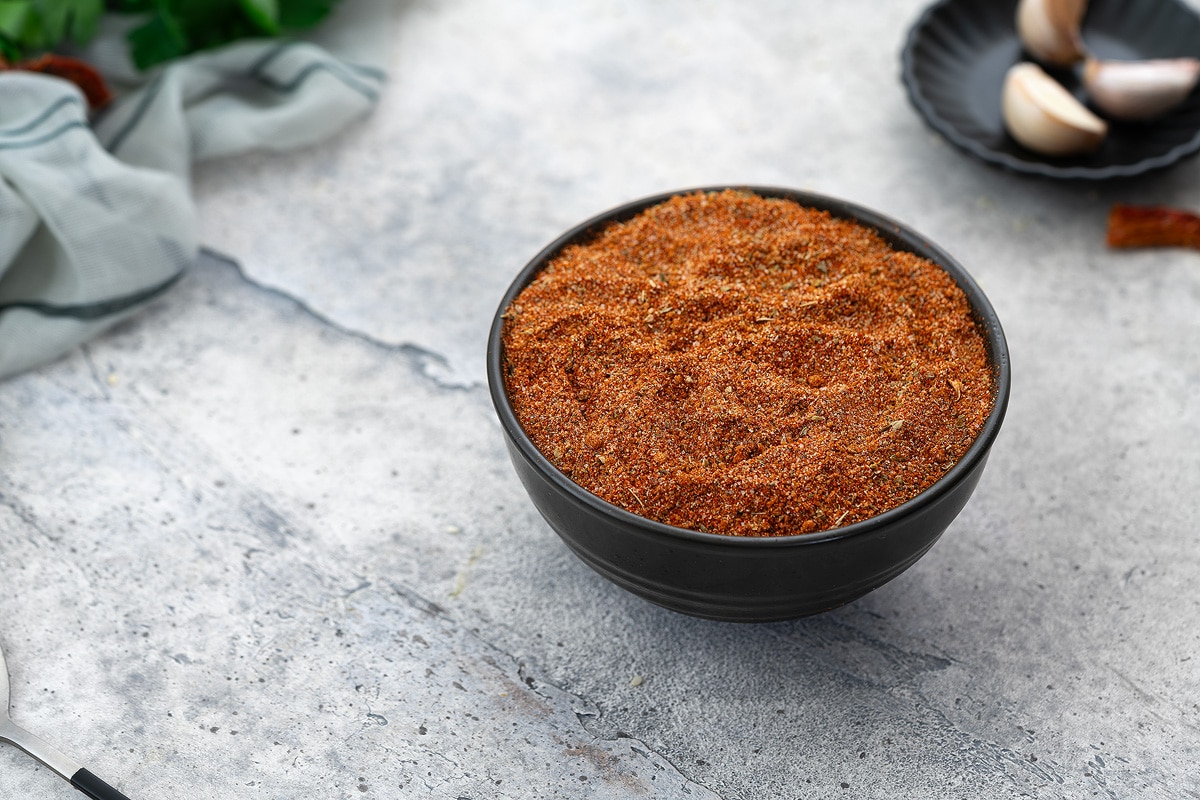 Chicken seasoning mix or dry rub in a black bowl on a white tabletop.