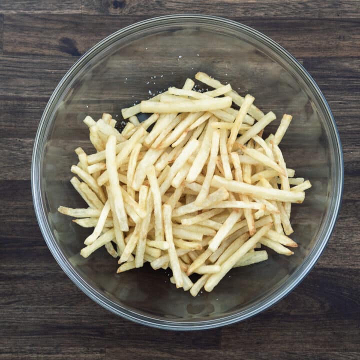 A bowl of French fries seasoned with salt.