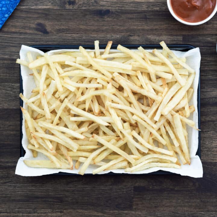 Crispy homemade French fries served in a tray with a side of ketchup.