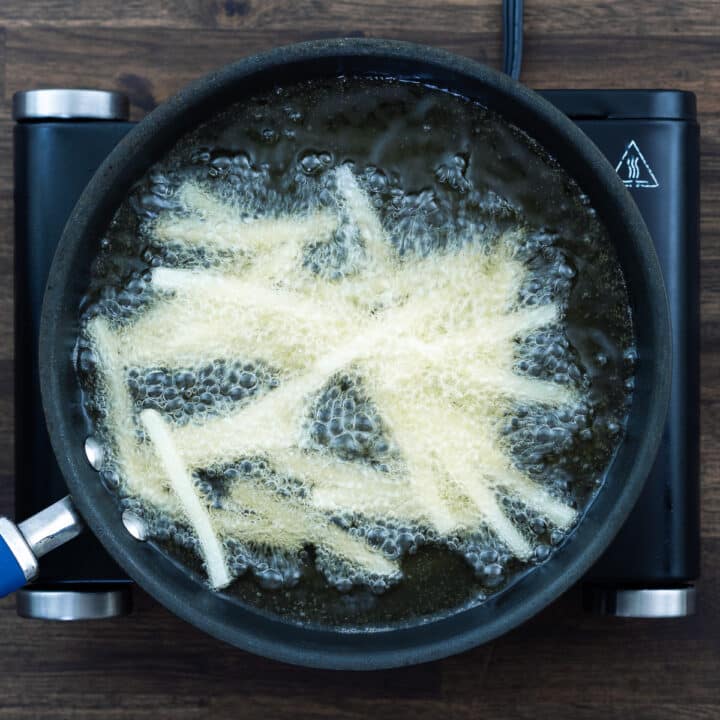 Potato strips frying in a hot oil.