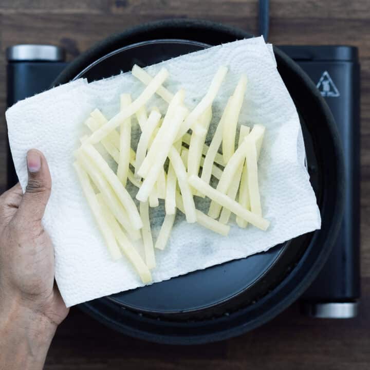 First fried French Fries on a plate lined with paper towel.
