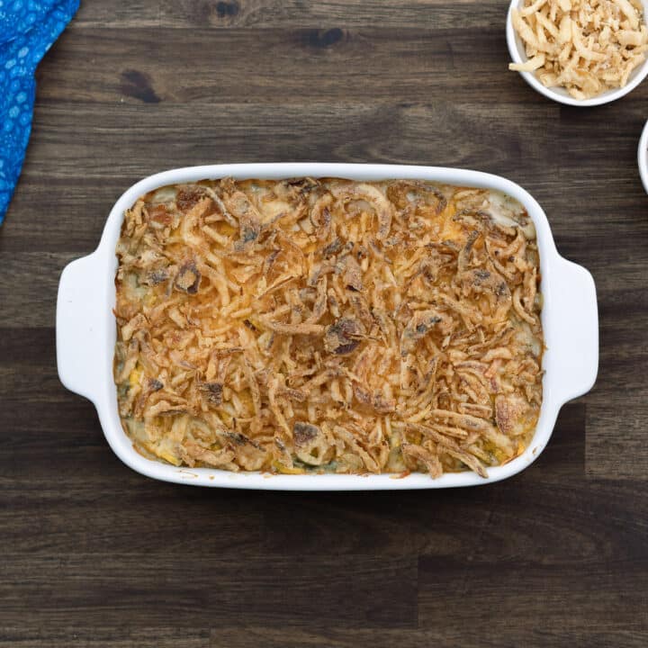Crispy and cheesy Green Bean casserole served along served on a brown table.