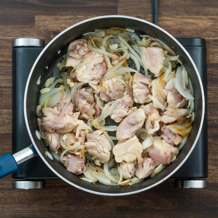 A pan with sauteed chicken and onions.