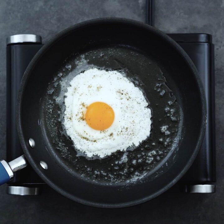 Sunny-side-up egg seasoned with salt and black pepper.