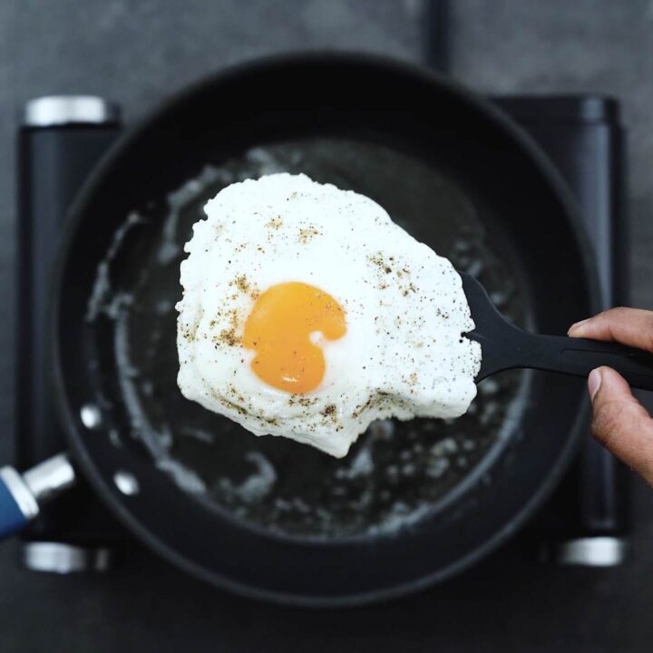Showing the sunny-side-up egg with a spatula.