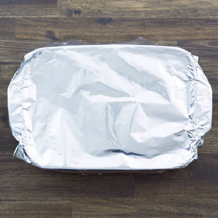 A baking dish with casserole mixture covered with aluminum foil.