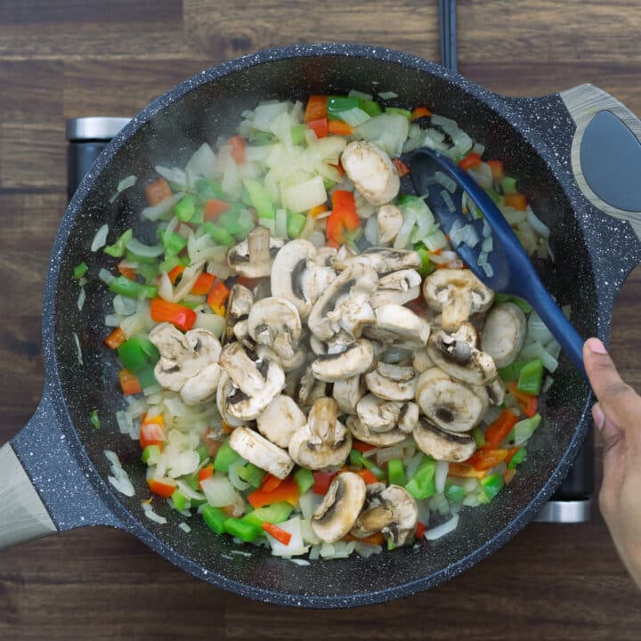 Sauteing mushrooms with onions and bell peppers.