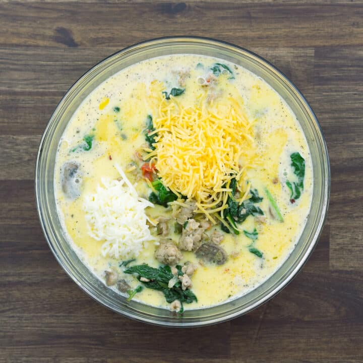 A bowl with whisked egg, veggie meat mix and cheese blend.