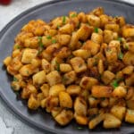 Breakfast potatoes in a grey plate on a white table top.