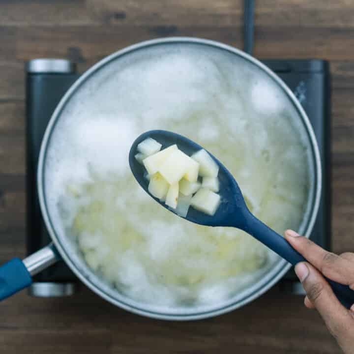 Showing the parboiled potatoes in a blue spoon.