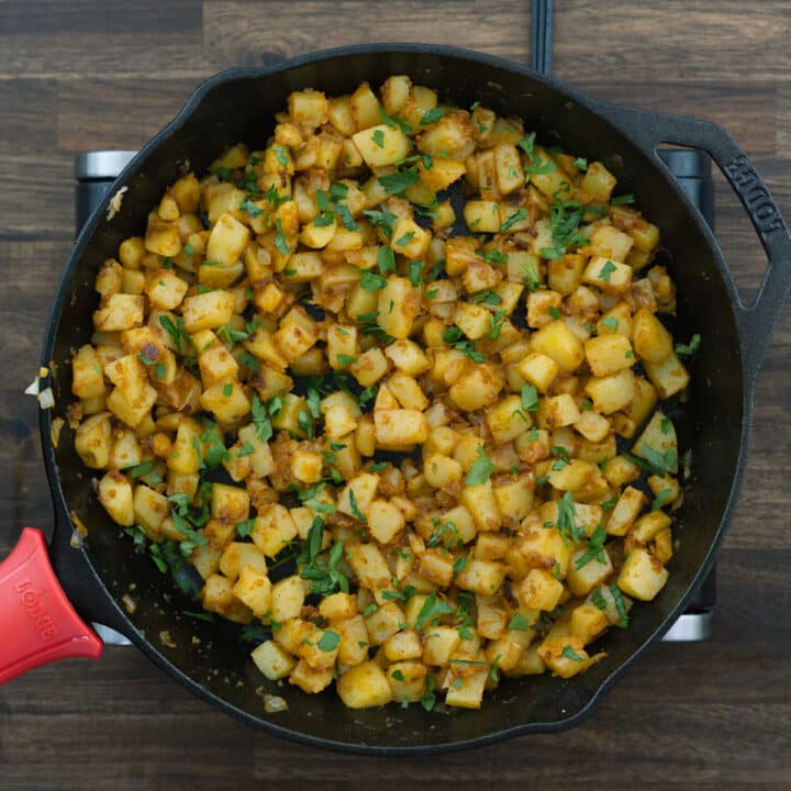 Breakfast Potatoes garnished with parsley leaves in an iron skillet.