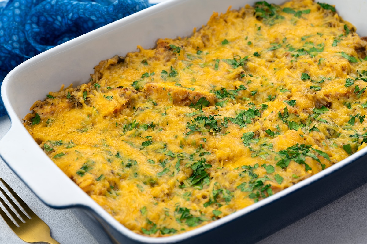 Chicken and rice casserole in a baking dish with a golden fork and blue towel placed around.