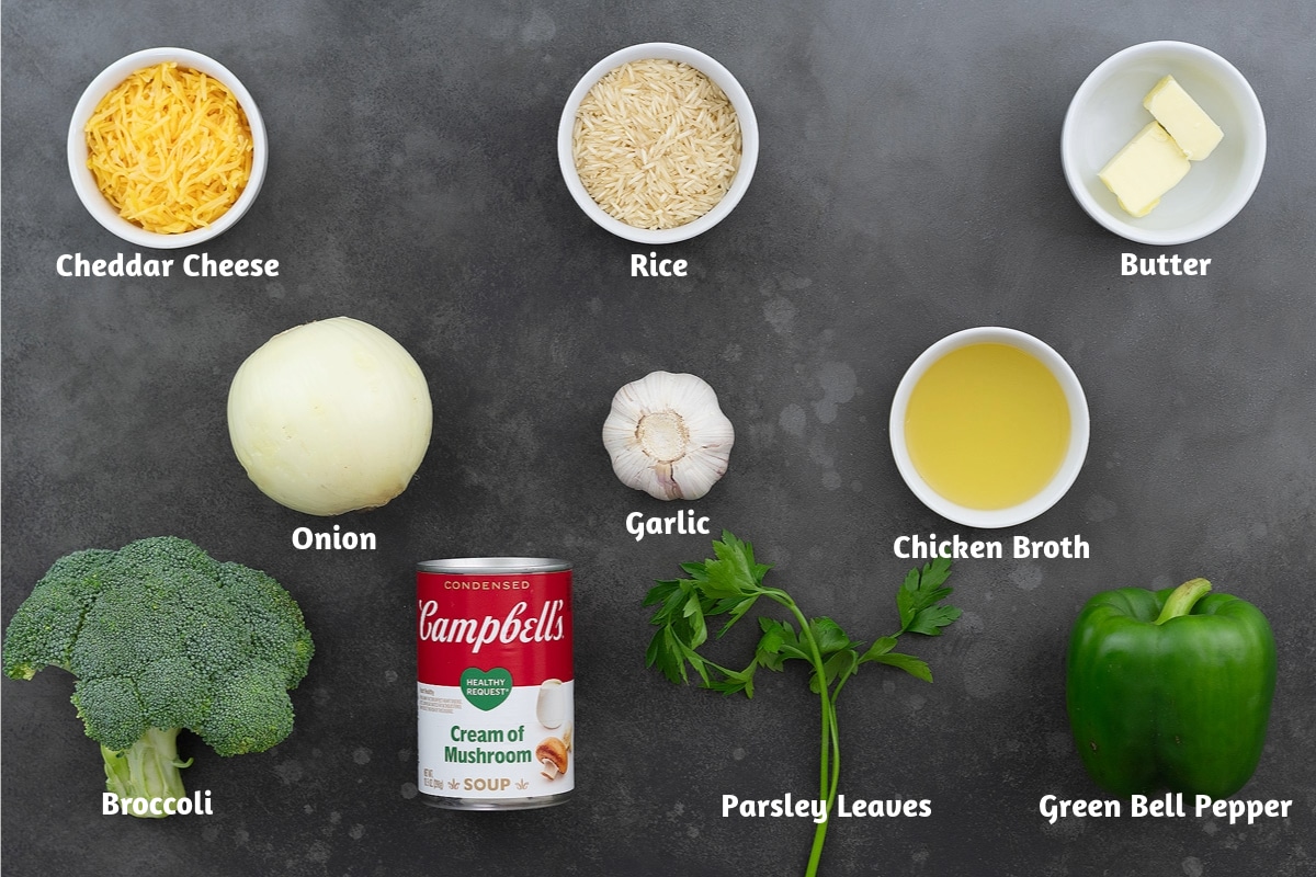 Ingredients for chicken and rice casserole, including cheddar cheese, rice, butter, onion, garlic, chicken broth, broccoli, cream of mushroom soup, parsley leaves, and green bell pepper.